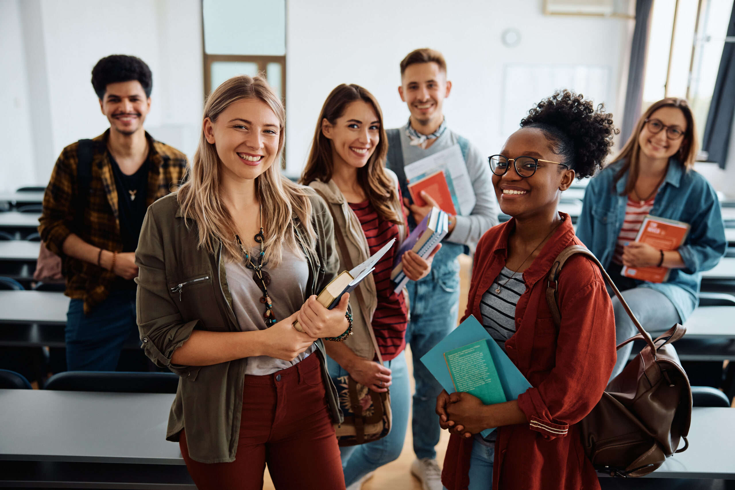 Multiracial group of happy college students int he classroom looking at camera.